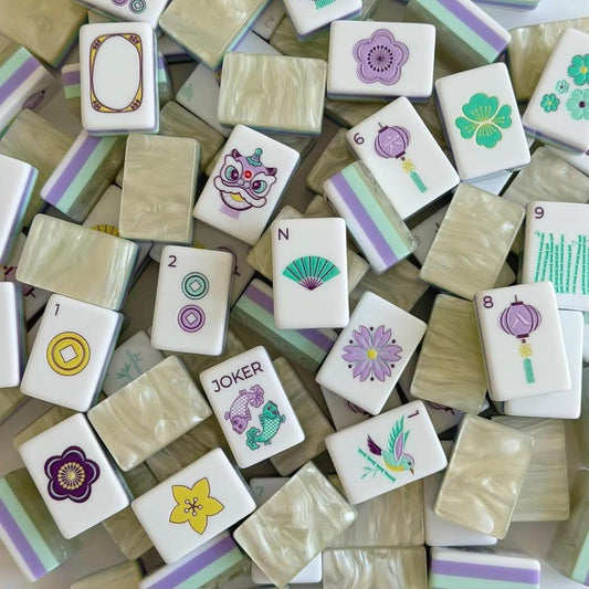 Bloom Garden American mahjong tiles scattered face up, with lavender, mint and yellow floral artwork, a fan wind, a lantern tile and a fish joker