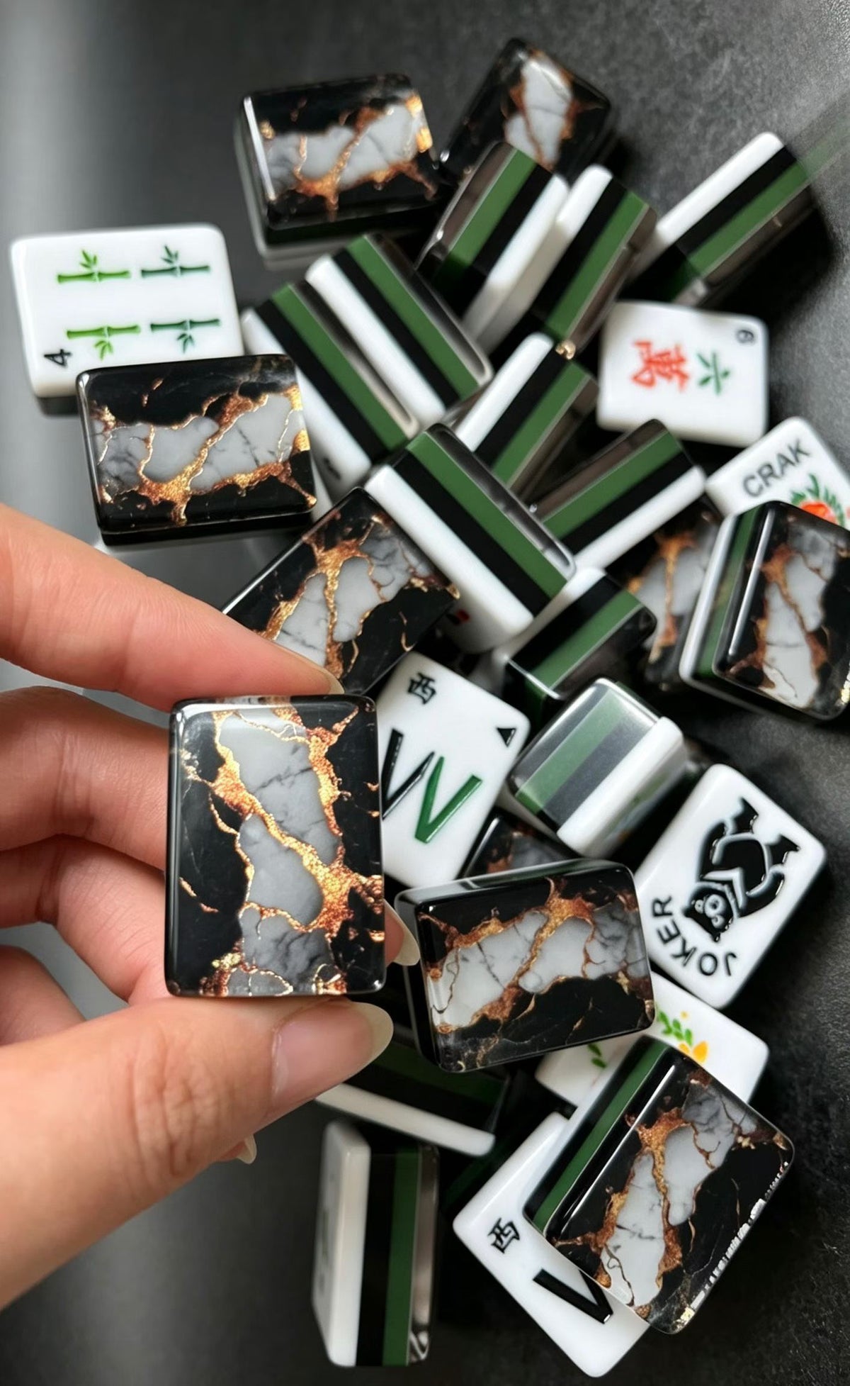 Gilded Obsidian acrylic American mahjong hand holding back over joker pile — panda joker and multi-layer stripe, Mahjong Loft