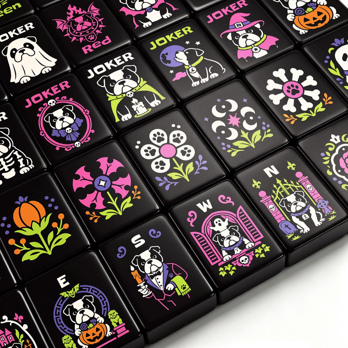 Close-up of gothic Halloween mahjong tiles featuring cute bulldog jokers, witches, ghosts, pumpkins, and floral designs in pink, purple, green, and orange on black tiles