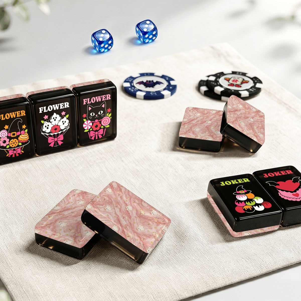 Gothic Dessert Halloween mahjong tiles styled with blue dice, bat and pumpkin poker chips, Flower and Joker tiles, and pink marble tile backs on beige linen tabletop