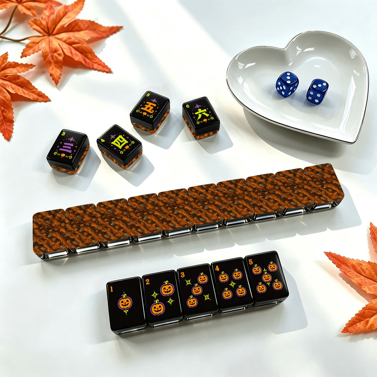 Pumpkin Hex Halloween mahjong set styled with autumn maple leaves, blue dice in a white heart dish, tile rack with orange pumpkin backs, and jack-o'-lantern dot tiles