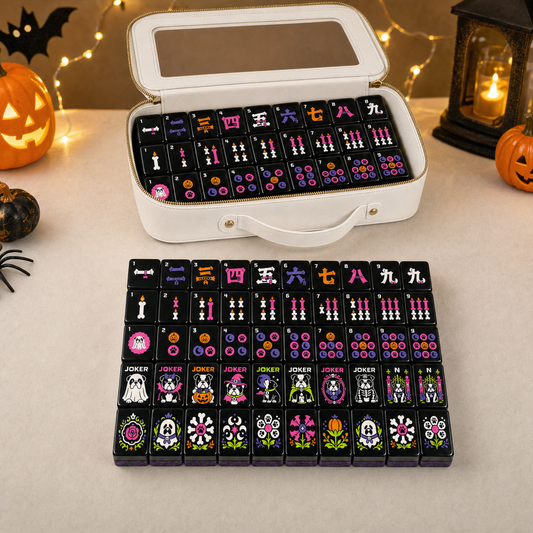 Wicked Bulldog Halloween Mahjong gift set styled lifestyle scene – open white carrying case with tiles displayed alongside a full row of gothic mahjong tiles, jack-o'-lanterns, string lights, lantern, and spider decorations – perfect Halloween hostess gift, October birthday, or American mahjong collector novelty